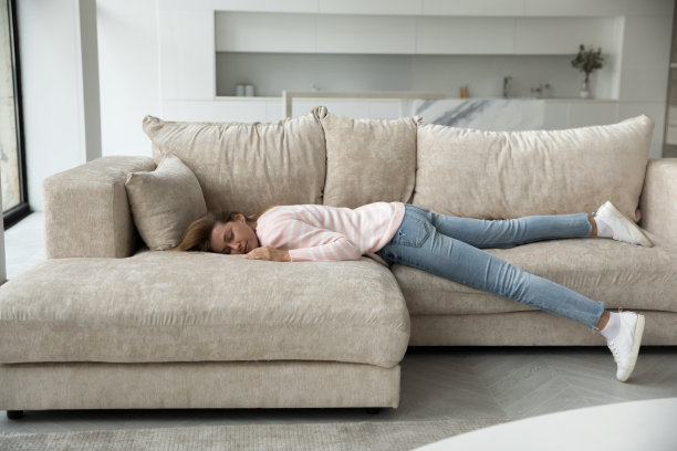 睡觉的年轻女子休息在家里的沙发全长度的镜头图片下载