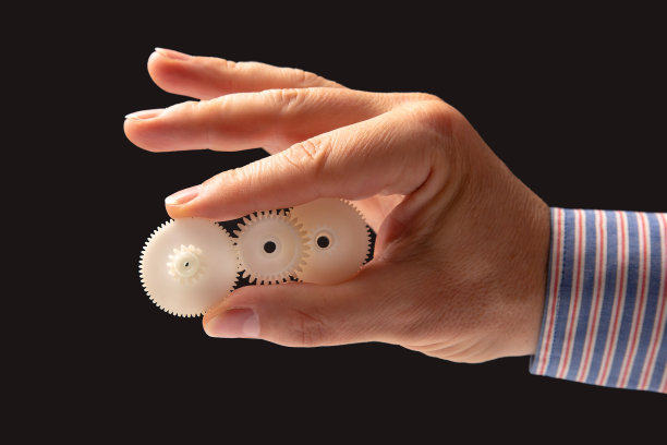 白色塑料齿轮在手。机器运动传动机构图片下载