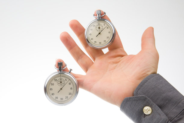 一个男人的手指上挂着两只机械秒表。时间精度。速度间隔的测量图片下载