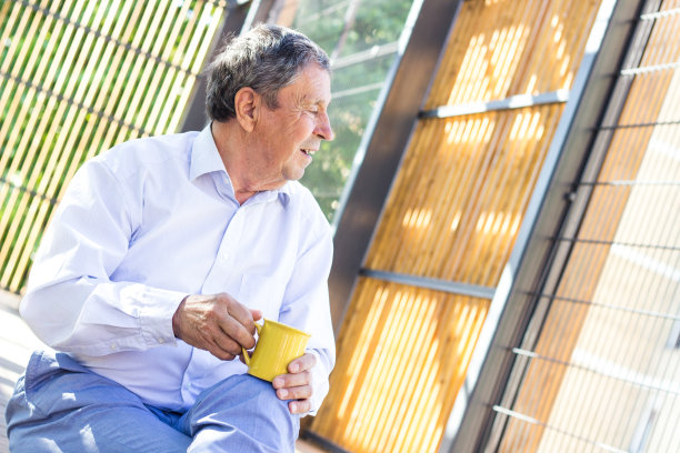 微笑的老人享受着早晨的咖啡图片下载