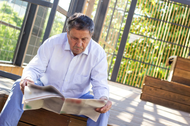 一位老人在户外看报纸图片下载