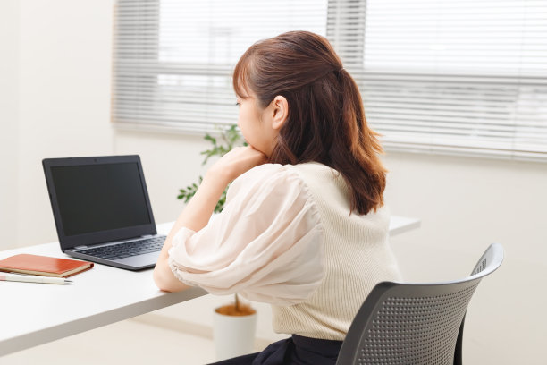 一位女士一边看着电脑屏幕一边用颧骨工作。她的表情是一种平静、不满和疲惫的形象。图片下载