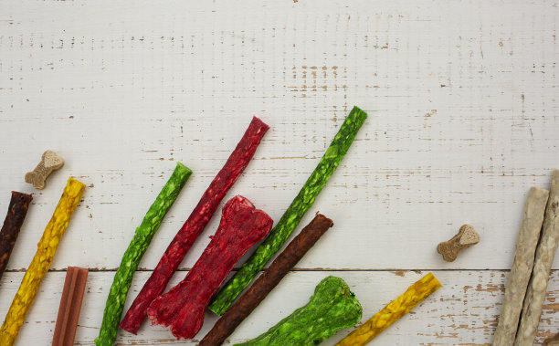 狗的蛇和骨头放在白色的木桌上。图片下载