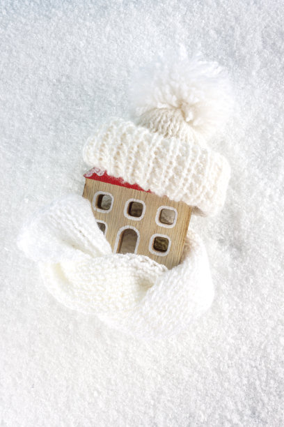 雪背景上的房子和暖和的衣服的身影。供暖季节的概念。图片下载