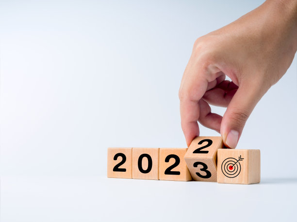 将日历年2022年改为2023年，目标和成功的概念。从2022年过渡到2023年的手工翻转木立方体块，目标图标标志隔离在白色背景上。图片下载