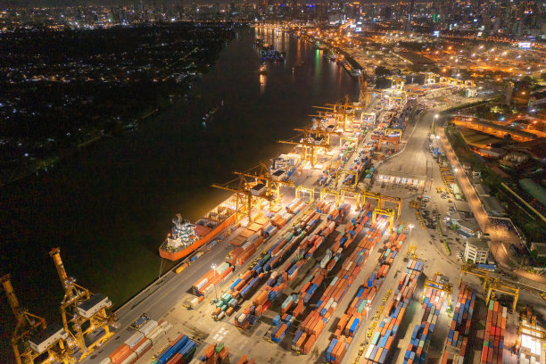 城市国际货物进出口及物流中的集装箱货船鸟瞰图。夜间，泰国曼谷港的起重机将货物运往港口。图片下载