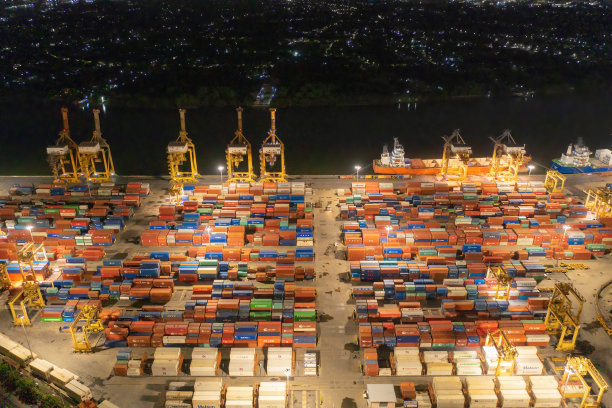 城市国际货物进出口及物流中的集装箱货船鸟瞰图。夜间，泰国曼谷港的起重机将货物运往港口。图片下载