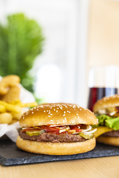 黑色石板上的经典美式汉堡和咖啡厅内部的可乐。不健康的街头食品。快餐。模糊的背景。图片下载