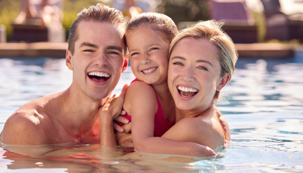 暑假微笑的一家人在游泳池里放松的画像图片下载