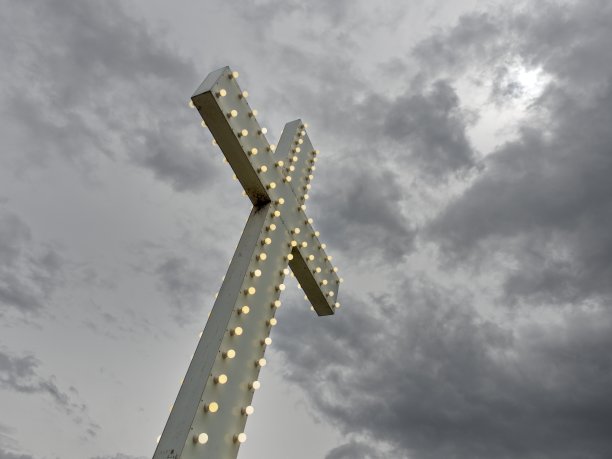 高大明亮的基督十字架站在暴风雨和不祥的黑暗天空背景图片下载