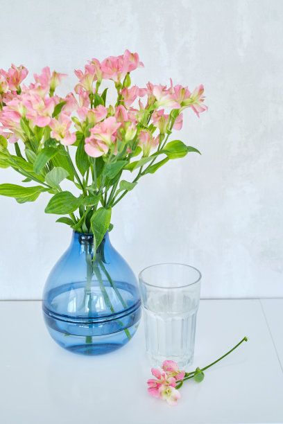 在明亮的背景上放有鲜花和透明的水的花瓶。透明的玻璃和干净的饮用水。健康的生活方式理念，护肤。一杯水的特写镜头图片下载