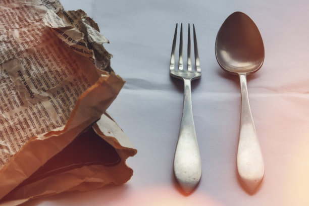 一把勺子和一把叉子放在一张旧报纸和烧焦的胶片上产生光效果图片下载