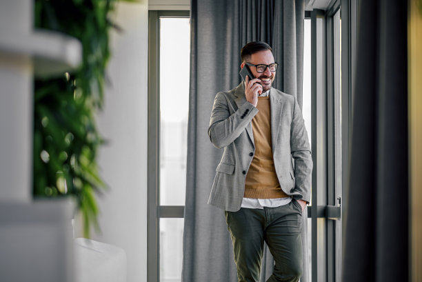 一个很高兴的企业家，站在走廊上打电话。图片下载