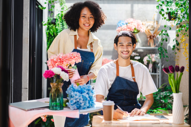 亚洲男性和非洲女性花匠花店老板工作和库存。一名男子在花店的桌子上用笔记本电脑打字。经营理念图片下载