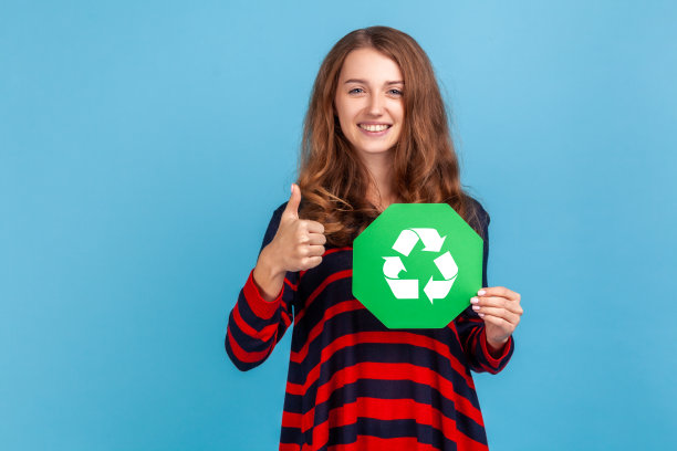 妇女手里拿着绿色回收标志，竖起大拇指，想着绿色。图片下载