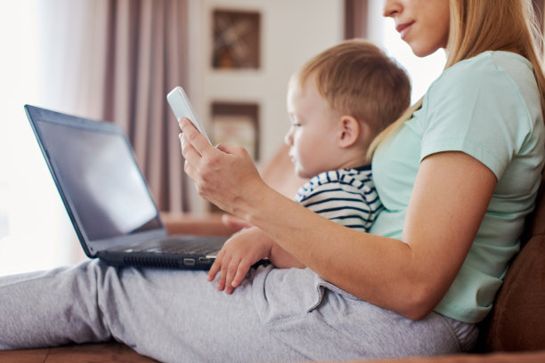 母亲拿着智能手机，笔记本电脑和一个婴儿图片下载