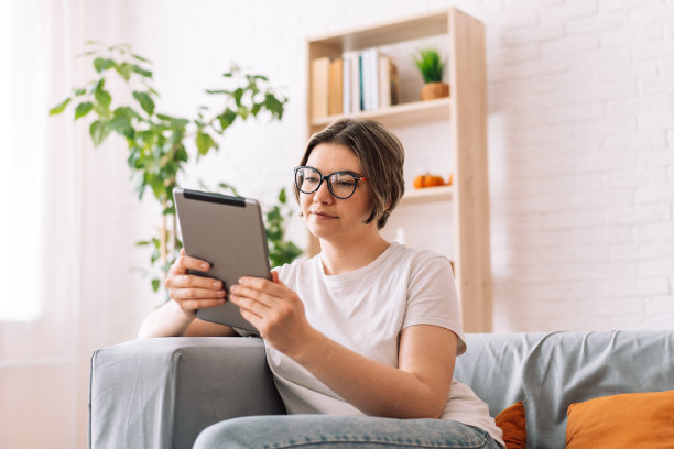 女孩坐在沙发上用平板电脑看书图片下载