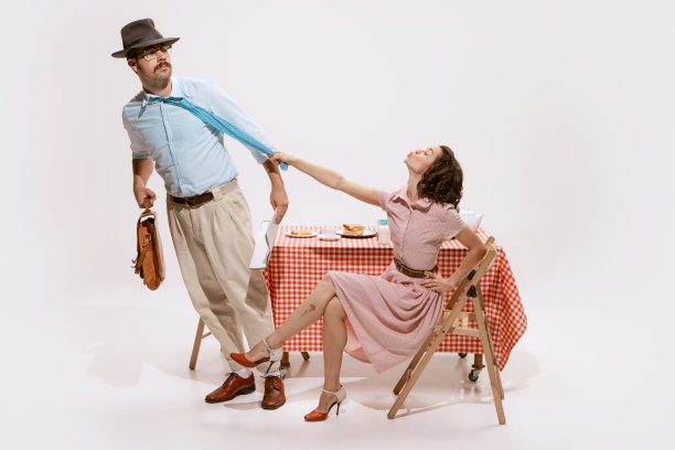 一对美丽的夫妇的肖像，妻子送别她的丈夫去工作在白色的背景。拉着领带亲吻图片下载