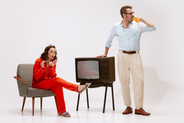 一对美丽的夫妇的肖像，女人穿睡衣画指甲，男人穿西装喝橙汁图片下载