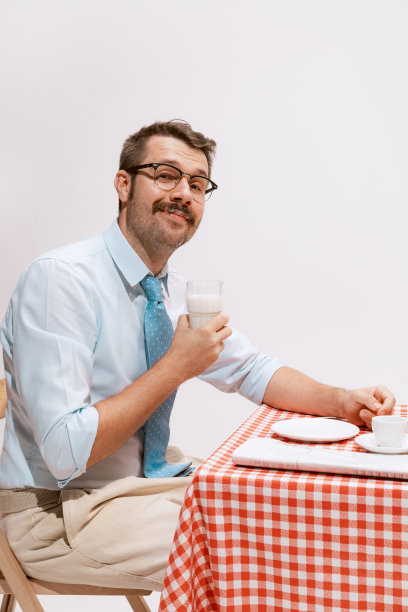 画像中穿着官服的男人面带微笑地坐在桌旁，拿着早餐。看起来平静愉快图片下载