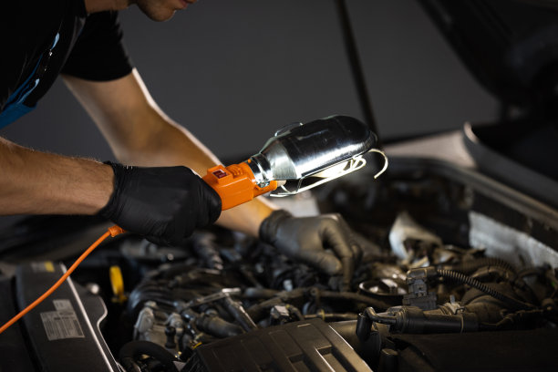 修车工正在汽车修理厂修理一辆汽车。戴着安全眼镜的修理工正在做一件普通的汽车保养工作。他挂着Led灯。现代车间图片下载