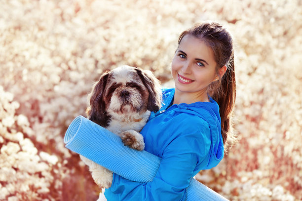 特写照片的运动妇女持有瑜伽马特和狗在手中图片下载