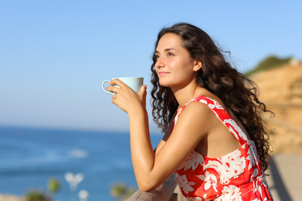 在海滩上喝咖啡的女人看向别处图片下载