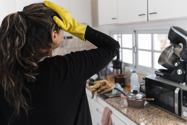 一名妇女担心她厨房里的混乱。关闭字幕图片下载