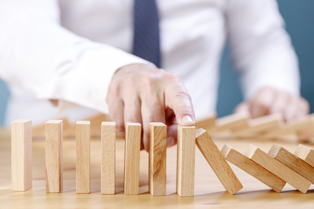 商人用风险的概念在多米诺骨牌上阻止木块的掉落图片下载