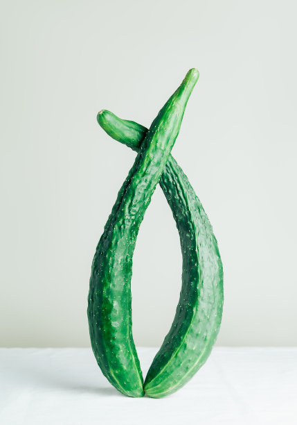 弯曲黄瓜的静物。丑陋的蔬菜。非常长的绿色黄瓜。图片下载