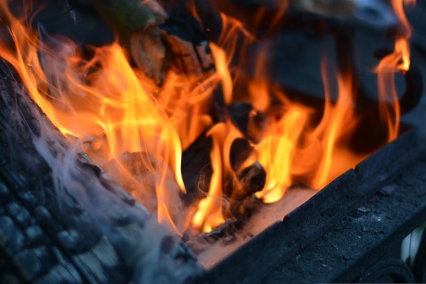 篝火烤架用于在篝火上的木炭上烧烤的火焰。灼热的木头和炭火在燃烧图片下载