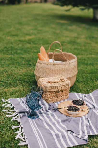 美丽浪漫的野餐，在绿色的草地上有蛋糕和两杯酒。图片下载