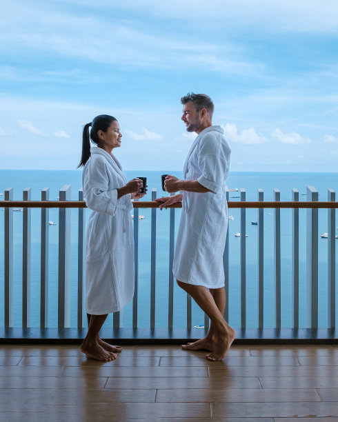 几个男人和女人在阳台上喝咖啡，窗外是芭堤雅的海湾图片下载