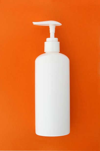 在一个橙色的背景上放着一个白色的瓶子和一个分配器。图片下载