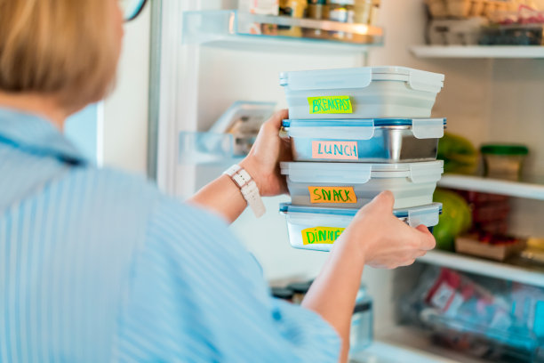 健康的减肥饮食计划，每日即食菜单。妇女拿或把提前做好的饭盒放进冰箱。生态健康食品容器。预煮的概念。图片下载