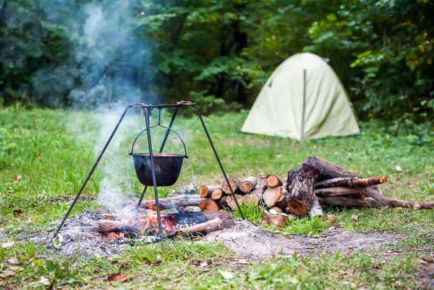夏天在大自然的营火上做饭。帐篷背景下的篝火和圆顶礼帽图片下载