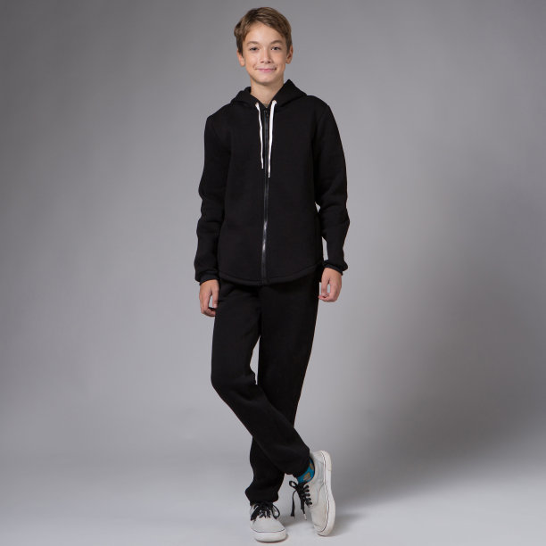一个十几岁的男孩，穿着黑色运动服，在灰色的背景下，正茁壮成长图片下载