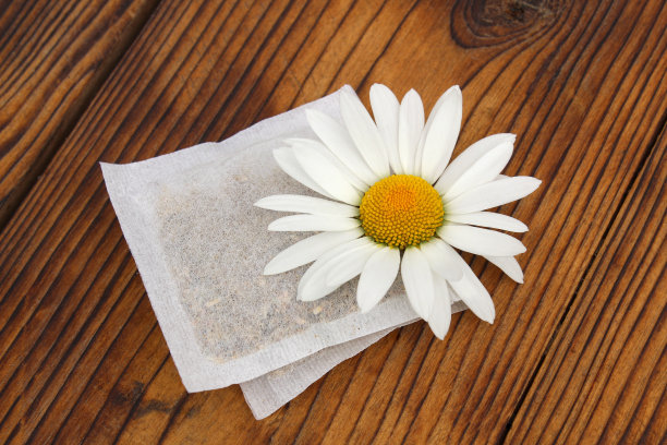 新鲜的洋甘菊和香辣的洋甘菊茶包躺在木背景。图片下载