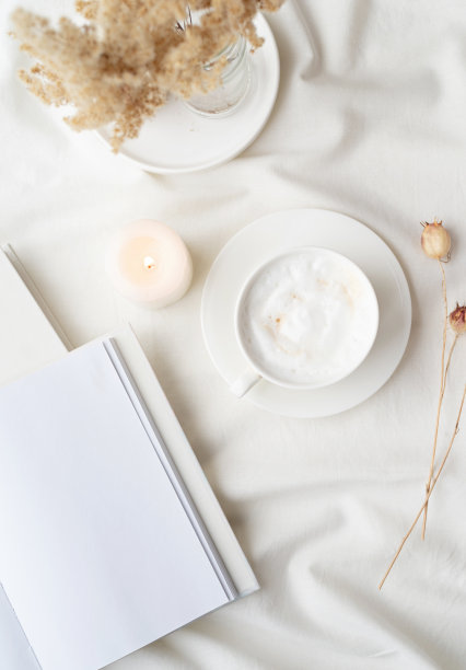 白色的空白书杯咖啡和燃烧的蜡烛，惬意的组成与打开的书模型图片下载