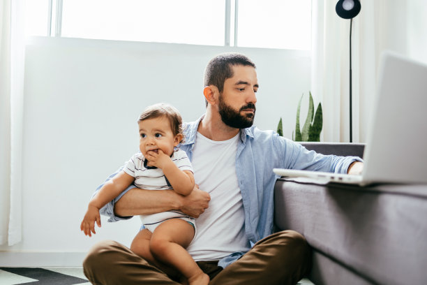 父亲和他的宝贝儿子在家庭办公室用笔记本电脑工作。在家办公的概念图片下载