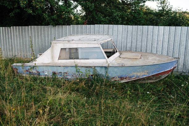 旧船的屋顶在草地上，背景是一个小金属栅栏。图片下载