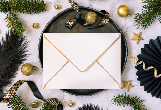 黑色和金色的圣诞餐桌设置，信封，饰品和杉木树枝。模型图片下载