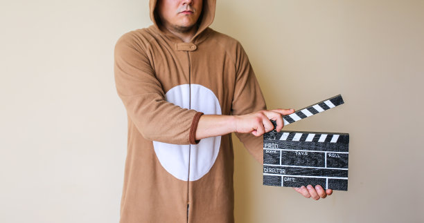 穿着cosplay服装的男人拿着黑色隔板。穿着滑稽动物睡衣的家伙在拍电影。导演和业余电影。创造性的概念。日本动漫。图片下载