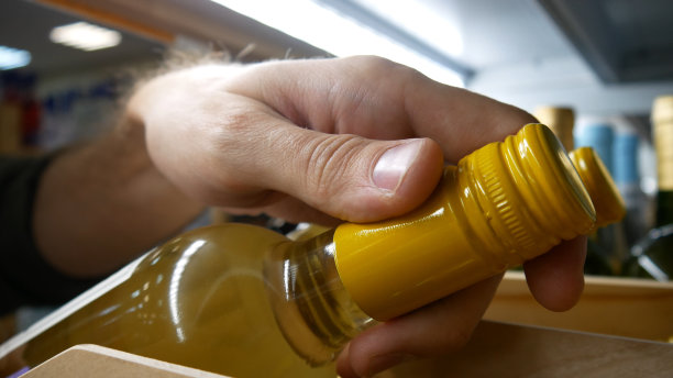 一个木制架子上漂亮的白葡萄酒瓶的特写，顾客的手拿着一瓶图片下载