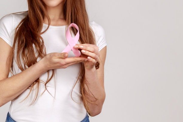 妇女的手和粉色丝带，象征乳腺癌意识。图片下载