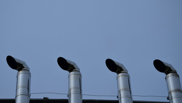 工业白色建筑，金属板立面重复矩形镶板。墙上有两根银光闪闪的烟囱管，管上有弯曲斜角的不锈钢管。燃气加热涡轮锅炉图片下载