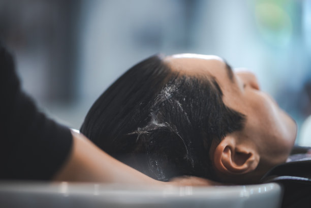 年轻男子在沙龙宠爱自己的头发水疗，理发和洗头沙龙图片下载