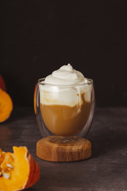 一杯秋季南瓜拿铁，加鲜奶油和香料。咖啡与南瓜和肉桂在黑暗的背景垂直照片图片下载