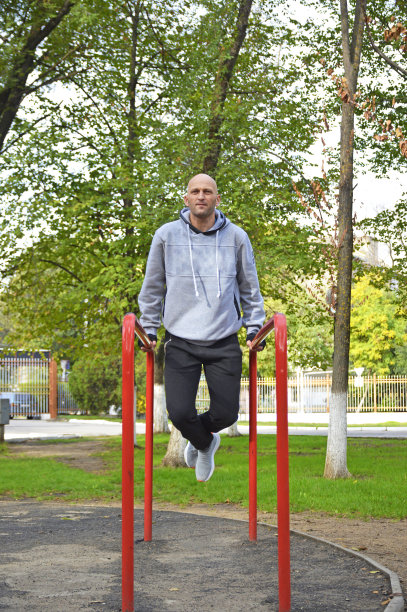 年轻肌肉发达的运动员训练高低杠，表演俯卧撑图片下载