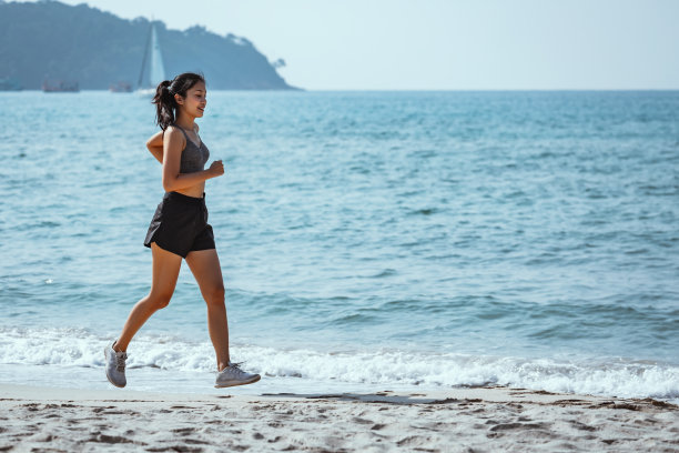 快乐的亚洲跑步女子独自在海滩上跑步图片下载